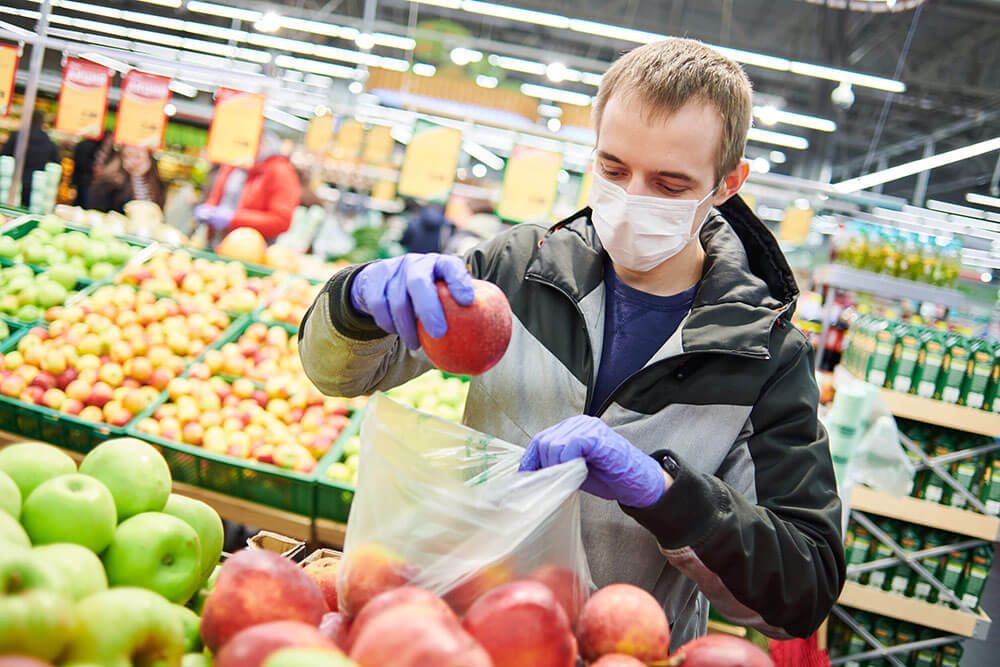 man in mask and protective gloves buying fruit food it supermarket shop during quarantine for covid-19 virus outbreak